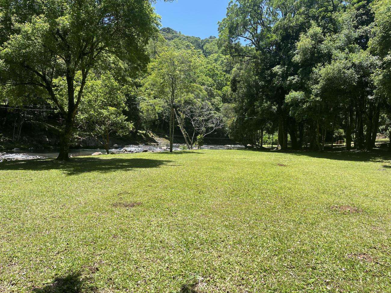 Gramado amplo ao lado do rio em dia de sol